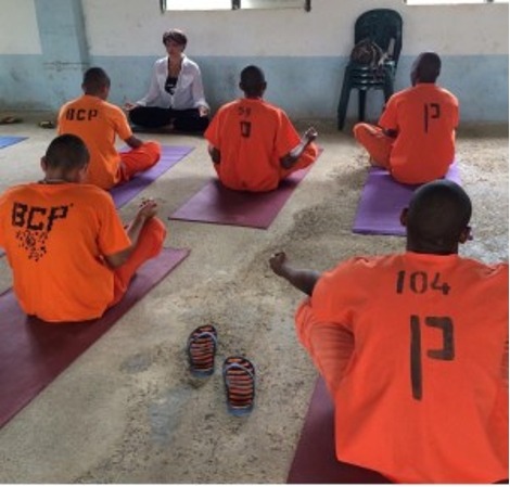 Yoga teacher and prison inmates seated on mats during meditation